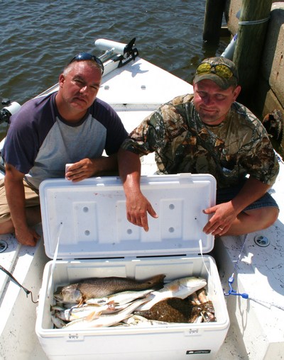 Tracy Sepulvado and jessie Smith pose with redfish, speckled trout, flounders, white trout, and ground mullet caught aboard TEAM BRODIE CHARTERS.