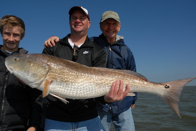 Graham, Tyler, and jerry Chapman display one of the many GIANT Reds that were caught while fishing with Capt. Mike